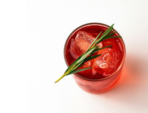 Photograph of a red cocktail in a glass on a white table